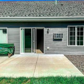 A house exterior featuring a sliding glass door leading to a concrete patio with grass in the foreground.
