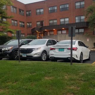 A view of parked cars in an urban parking lot with a building in the background.
