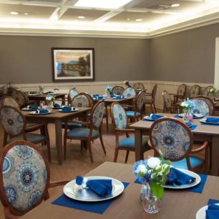 A stylishly decorated dining room with elegant tables and chairs, featuring blue placemats and decorative table settings.