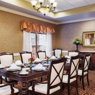 An elegantly set dining room with a large table, upholstered chairs, and a chandelier.