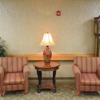 A cozy seating area with two striped chairs and a table featuring a lamp.