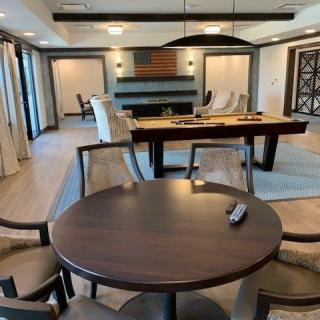 A modern living room with a pool table, round table, and comfortable seating.