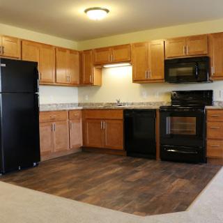 A modern kitchen featuring wooden cabinets, black appliances, and a spacious layout.
