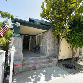 A small residential house with a porch, displaying an American flag and surrounded by trees.