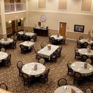 An elegant dining area with round tables and chairs neatly arranged on a carpeted floor.