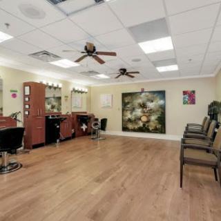 A spacious and well-lit salon featuring barber chairs, a waiting area, and ceiling fans.