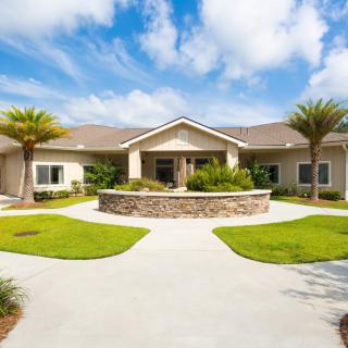 A modern residential house with a landscaped front yard and palm trees.