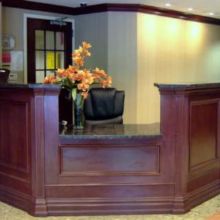 An elegant wooden reception desk with a flower arrangement.
