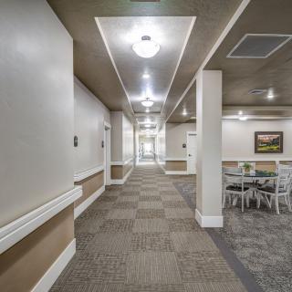 A well-lit hallway with carpeted flooring and a seating area.