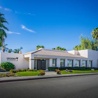 A modern office building surrounded by palm trees under a clear blue sky.