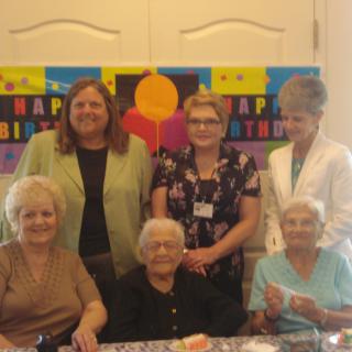 A group of elderly women celebrates a birthday with smiles and joy.