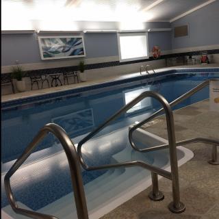 An empty indoor swimming pool with metal handrails and a calm atmosphere.