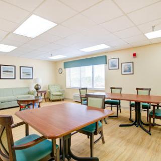 A well-lit lounge area featuring wooden tables and comfortable seating, designed for relaxation and socializing.