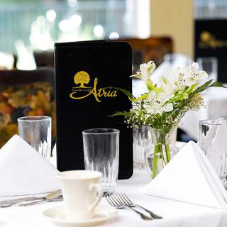 An elegantly set restaurant table with a menu and flower arrangement.