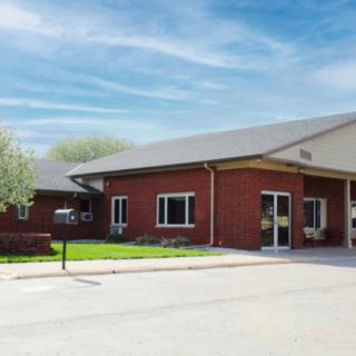 A brick commercial building with a parking area under a blue sky.
