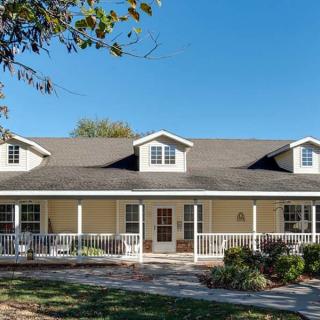 A large residential house with a spacious front porch and multiple dormer windows.