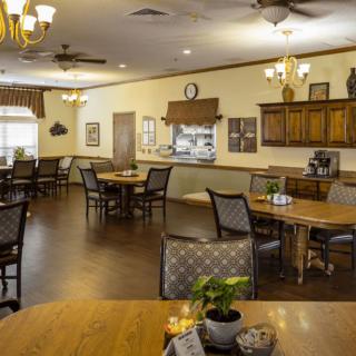 A cozy dining room with neatly arranged tables and chairs, warm lighting, and tasteful decor.