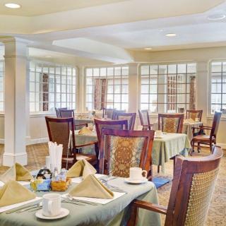 A well-decorated dining area with neatly arranged tables and chairs, featuring elegant table settings.