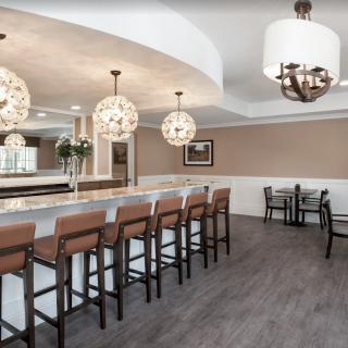 A modern bar area with pendant lighting and seating at the counter.