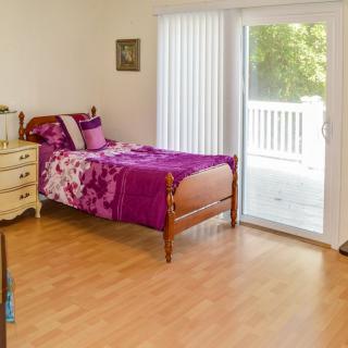 A cozy bedroom with a single bed and a view of the balcony through sliding glass doors.