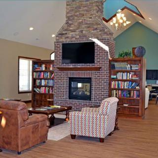 A cozy living room with a brick fireplace, bookshelves, and comfortable seating.