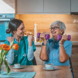 A healthcare worker and a senior woman exercising with dumbbells in a cozy indoor setting.