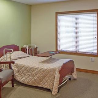 A hospital room with a bed, wheelchair, and a window.