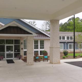Entrance of a modern building with a covered area and seating.