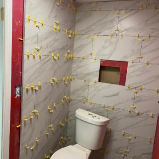 A partially renovated bathroom featuring a toilet and tiled walls.