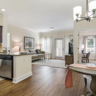 A modern open floor plan featuring a kitchen, living room, and dining area with hardwood floors and ample natural light.