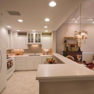 A modern kitchen with white cabinets and ambient lighting, featuring an open layout.