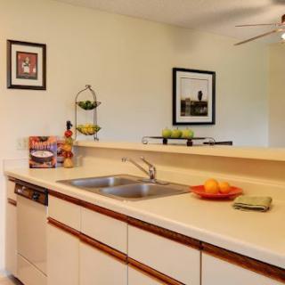 A modern kitchen featuring a clean countertop with fresh fruits and decorative wall art.