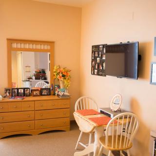 Cozy room with a dresser, mirror, wall-mounted TV, and small dining area.