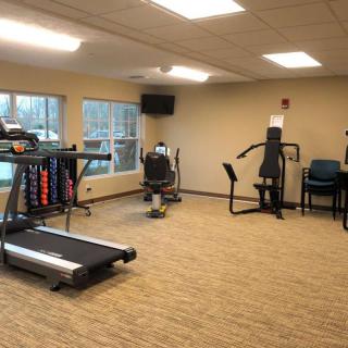 A small indoor gym with various exercise equipment including a treadmill and weights.