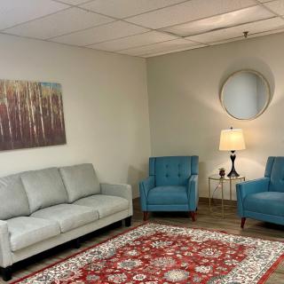 A cozy living room with a sofa, two blue armchairs, and a decorative rug.