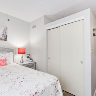 A cozy bedroom featuring a bed with floral bedding, a red lamp, and a sliding door closet.