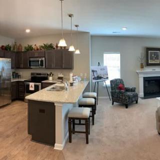 A modern open-concept kitchen and living room with an island counter and a cozy seating area by the fireplace.