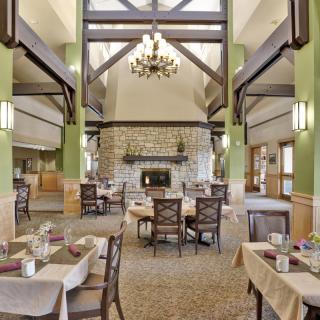 A spacious dining room with elegant decor, featuring a central fireplace and a chandelier.