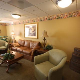 A cozy waiting room with comfortable sofas and armchairs, warm lighting, and decorative plants.