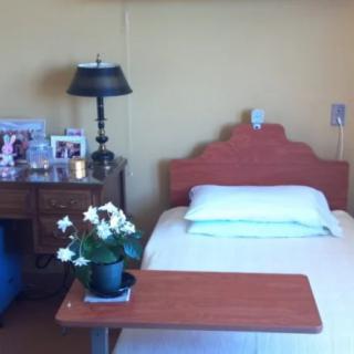 A hospital room with a single bed, side table, and personal items displayed.