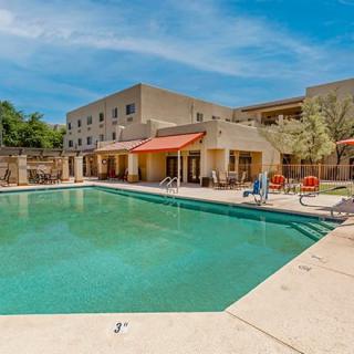 An outdoor swimming pool area at a hotel with clear blue skies.