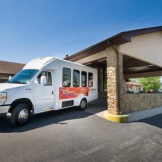 A shuttle van parked in front of a building driveway on a sunny day.