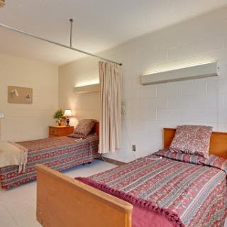 A cozy bedroom featuring two twin beds with simple decor and warm lighting.