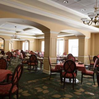 An elegant empty dining room with chandeliers and neatly arranged tables and chairs.