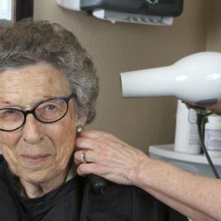 An elderly woman is getting her hair styled at a salon.
