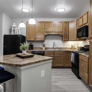 A modern kitchen featuring wooden cabinets, a central island, and contemporary appliances.