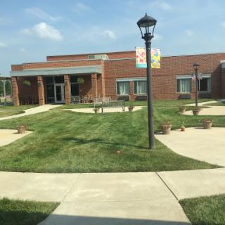 A well-maintained outdoor area featuring a building, landscaped grass, and a lamp post under a sunny sky.