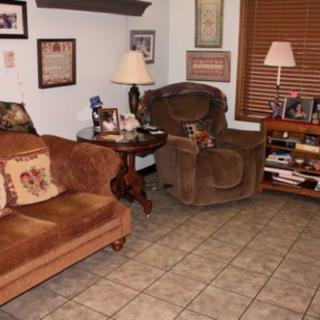 A cozy living room with a couch, armchair, and various decorations.