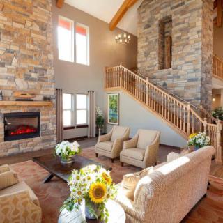 A spacious living room with a stone fireplace, high ceiling, and elegant furniture.