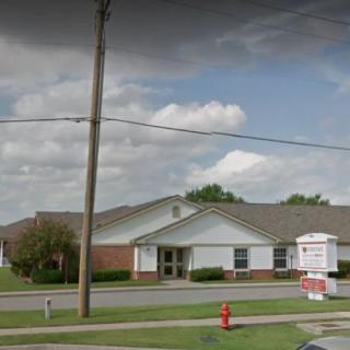 A clinic building with a sign and a cloudy sky in the background.